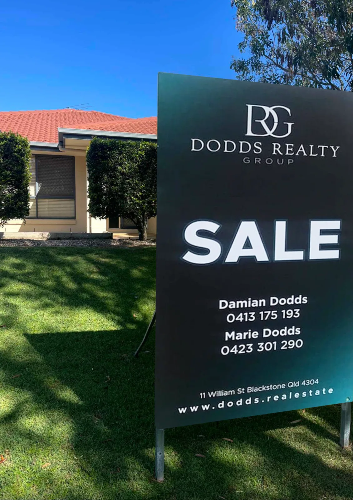 Dodds Realty Group sale signboard in front of a tiled-roof home